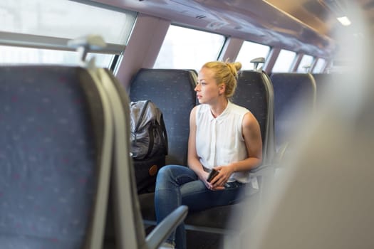 Young woman looking trough window while traveling by train.