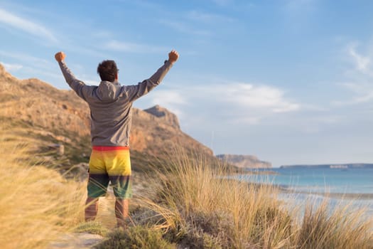 Sporty active man, arms rised, enjoying beauty of nature, freedom and life at beautiful landscape. Active lifestyle outdoors. Made it.