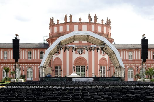 Wiesbaden,Germany – July 14,2016: A concert stage with rows of seats for a classical concert on the castle grounds with Biebrich Castle in the background on July 14,2016 in Wiesbaden.