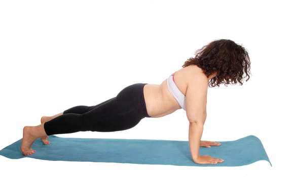 A young woman doing puchup's on a blue matt with curly brunette.hair wearing exercise outfit, isolated for white background..