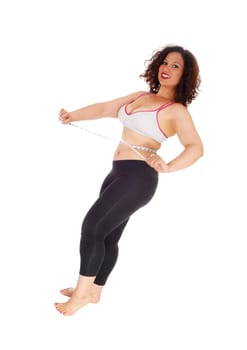 A pretty woman in exercise outfit standing and measuring her stomach.smiling she is happy, isolated for white background..