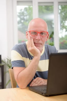 a mature man with laptop in his home