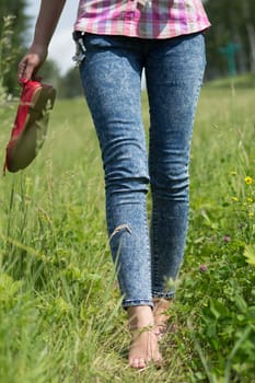 Beautiful young female legs walking on the grass in summer