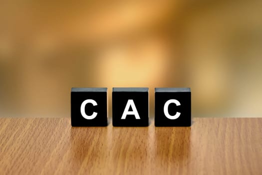 CAC or customer acquisition cost on black block with blurred background