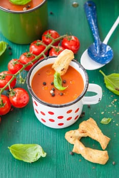 Fresh tomato soup with basil in rustic cup