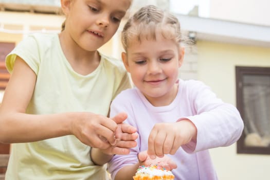 Two girls sprinkle confectionery on Easter cupcakes