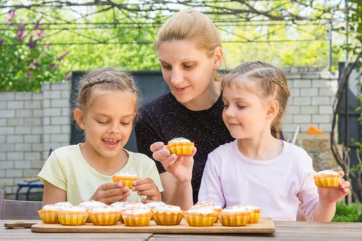 Mother and two daughters sitting at the table with Easter cupcakes and they are risen