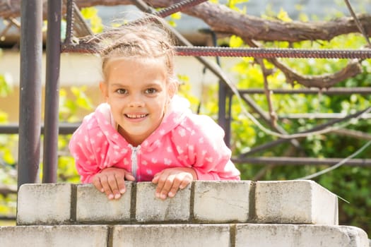 Seven Years' happy girl hanging on a brick fence and looked in the frame
