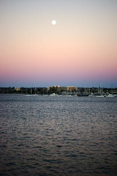A colorful sunrise in San Diego Bay under the full moon.