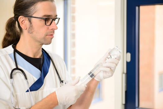 long haired male nurse prepare a liquid medicament