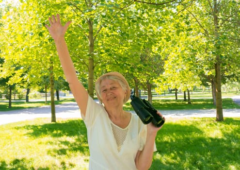 Senior woman with binoculars in the park