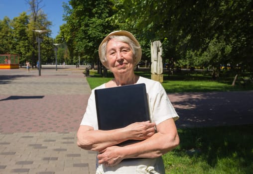 Senior woman with laptop in summer green park