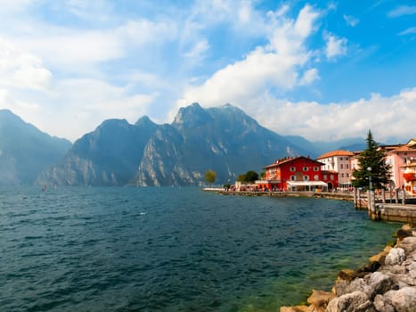 Torbole, Italy - September 21, 2014: Lake Garda boardwalk with houses, tourists and boats in Torbole, Italy. Torbole is one of the most popular towns on Garda Lake, known as a wind surfers paradise.