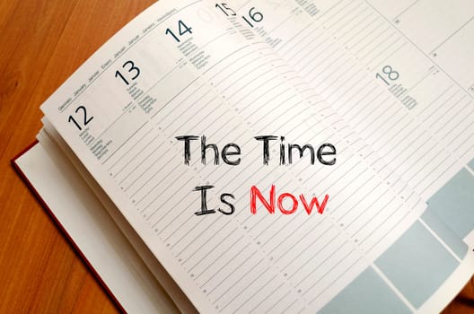 The time is now text concept write on notebook