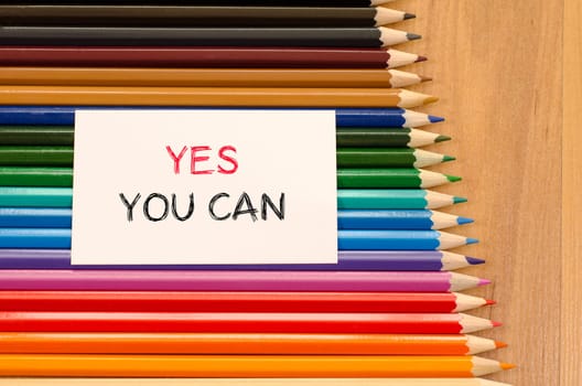 Blank white paper and colored pencil on wooden background