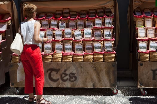 Granada, Spain - August 5, 2016: tourist buying spices, seeds and tea sold in a traditional street market
