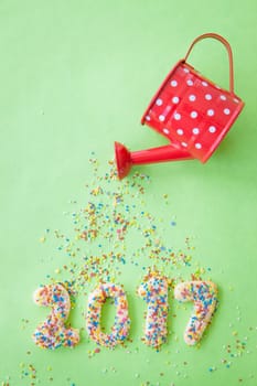 Biscuits with colorful sprinkles for New Year 2017 on a green background