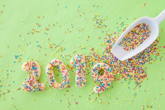 Cookies with colorful sprinkles for the New Year 2019 on a green background