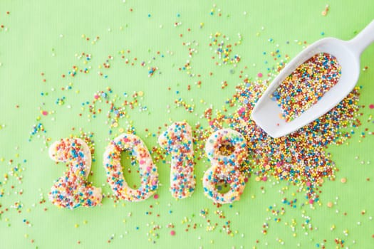 Cookies with colorful sprinkles for the New Year 2018 on a green background