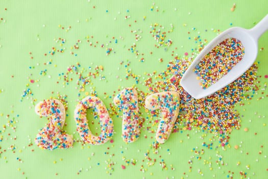 Cookies with colorful sprinkles for the New Year 2017 on a green background