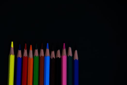 colorful pencils isolated on a black background paper
