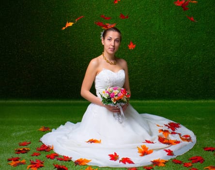 Young and beautiful bride with the flower bouquet and  falling red maple leaf the green background