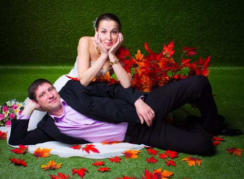 Bride and groom sitting together on a green background and red maple leaf