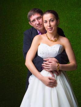 Happy pregnant bride and groom embracing together with stomach unborn child