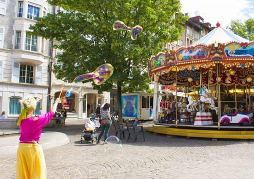 Geneva, Switzerland - June 17, 2016: The children and with soap bubbles attraction near the city carousel in the old town of Geneva, Switzerland on 28 July, 2010. It is the second most populous city in Switzerland.