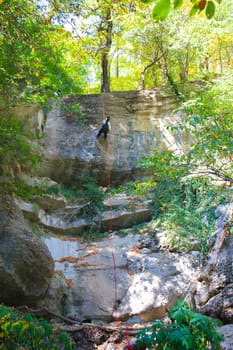 Woman climbing on steep the mountain slope. Mountains in Crimea at the sunny summer day.