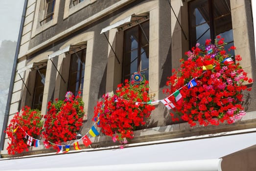 Vintage window with flowers and flags in old house, Geneva, Switzerland