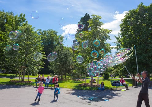 Geneva, Switzerland - June 17, 2016: The children and with soap bubbles attraction at park in the old town of Geneva, Switzerland on 28 July, 2010. It is the second most populous city in Switzerland.