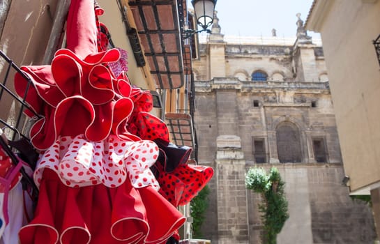 Street beside Granada Cathedral in the old town with shops selling souvenirs typical flamenco dresses, Spain