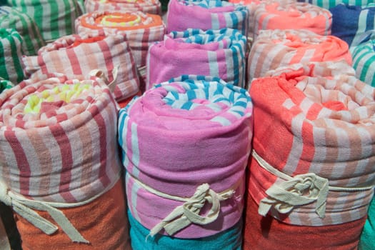 Loads of many rolled colorful light cotton blankets. Closeup