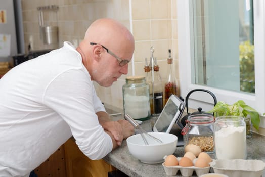 a mature man with a tablet in the kitchen