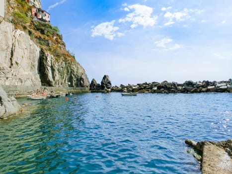 Manarola, Cinque Terre, Italy - September 09, 2015: The boats near a rock at Mediterranean sea at Manarola, Cinque Terre, Italy