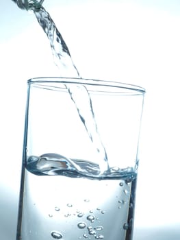 Pouring fresh table water in a glass, blue toned healthy concept image