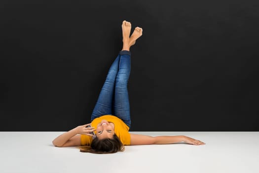 Beautiful young woman sitting in the floor in front of a dark wall