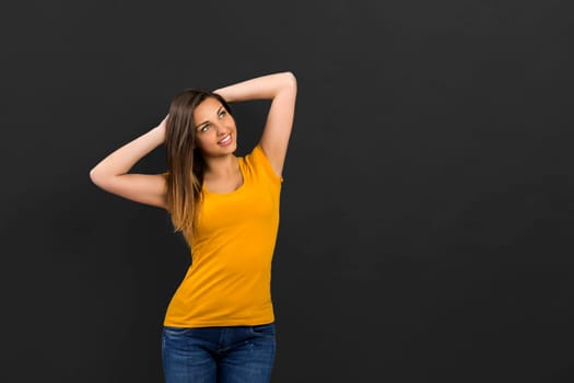 Beautiful woman in front of a black wall with a thoughtful expression