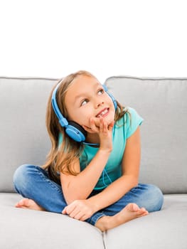 Little blonde girl at home listen music with headphones