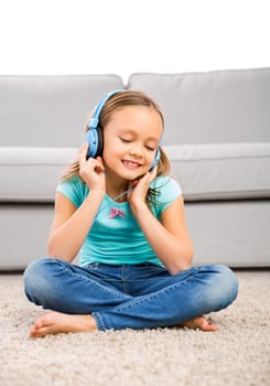 Little blonde girl at home listen music with headphones