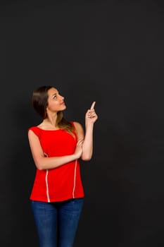 Beautiful woman standing in front of a dark board and pointing