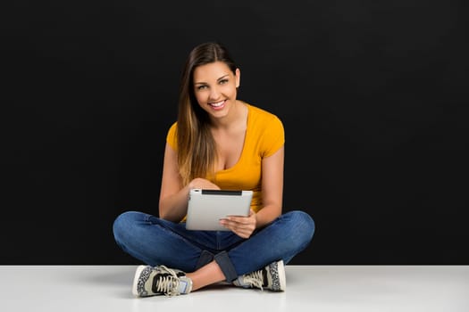Beautiful woman sitting on the floor working with a tablet