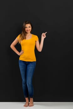 Beautiful woman standing in front of a dark board and pointing