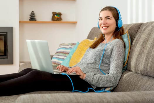 Beautiful woman working at home with a laptop while listen music and drinking coffee