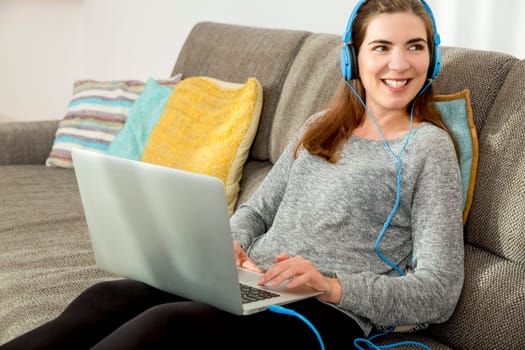 Beautiful woman working at home with a laptop while listen music and drinking coffee