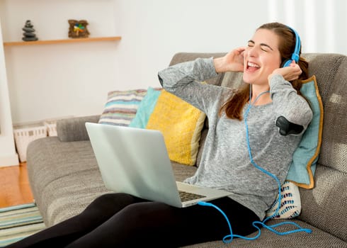 Beautiful woman working at home with a laptop while listen music and drinking coffee