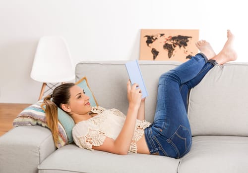 Beautiful woman at home sitting on the couch and reading a book