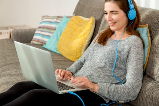 Beautiful woman working at home with a laptop while listen music and drinking coffee
