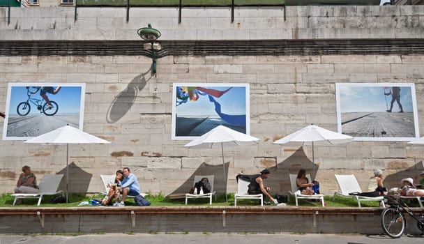 people lying in the sun on the banks of the seine in paris